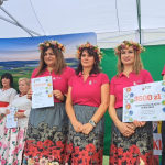 Laureatki II miejsca: Koło Gospodyń Wiejskich  Pławnianki pozują na scenie razem z nagrodą i dyplomem.