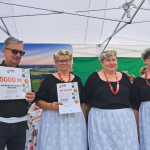 Laureaci I miejsca - Koło Gospodyń Wiejskich Twórcza Osada w Biadaszcach  pozują na scenie do zdjęcia wraz z przedstawicielem komisji konkursowej oraz z  dyplomem i nagrodą.