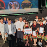 Grupa osób pozują wspólnie na scenie do pamiątkowego zdjęcia