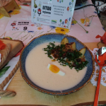 Stół z plakietką Koło Gospodyń Wiejskich w Zwierzyńcu Pierwszym oraz talerzem zwycięskiej potrawy „Poliwka z maślanki z wędzonymi ziemniakami i jajkiem na twardo" 